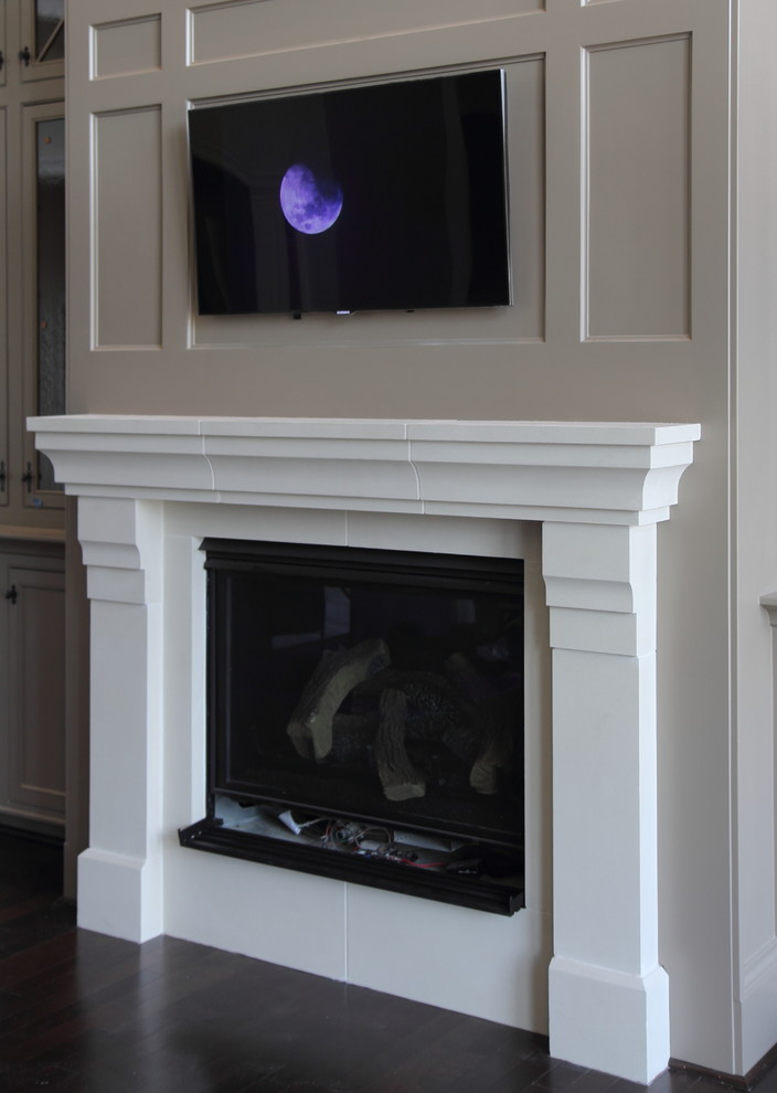 This is an example of a traditional living room in Houston with a standard fireplace and a concrete fireplace surround.