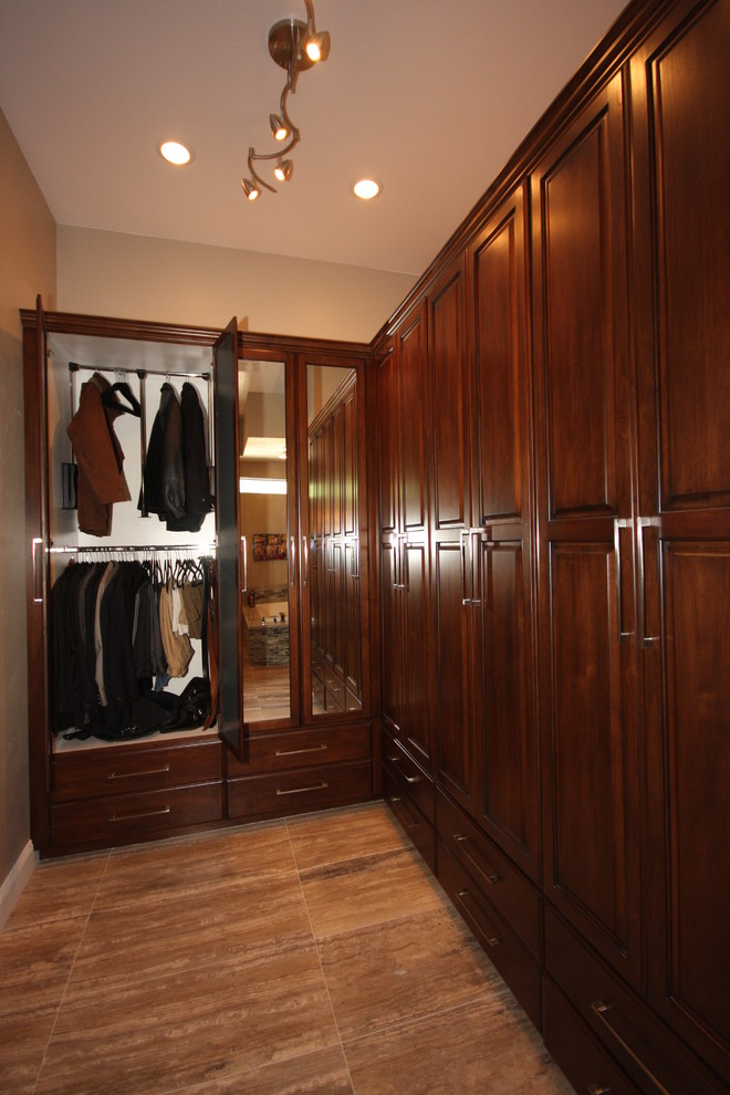 This is an example of a mid-sized contemporary gender-neutral walk-in wardrobe in Las Vegas with raised-panel cabinets, dark wood cabinets, porcelain floors and brown floor.