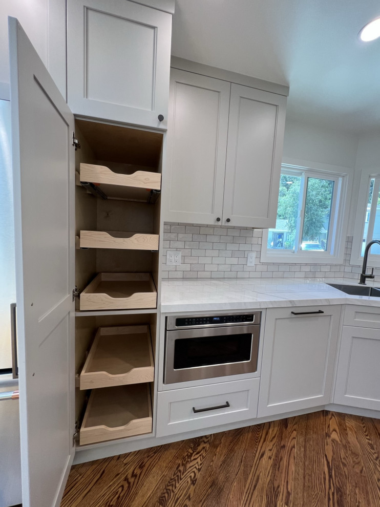 Photo of a mid-sized midcentury galley kitchen pantry in San Francisco with a double-bowl sink, shaker cabinets, grey cabinets, solid surface benchtops, white splashback, ceramic splashback, stainless steel appliances, medium hardwood floors, brown floor and white benchtop.