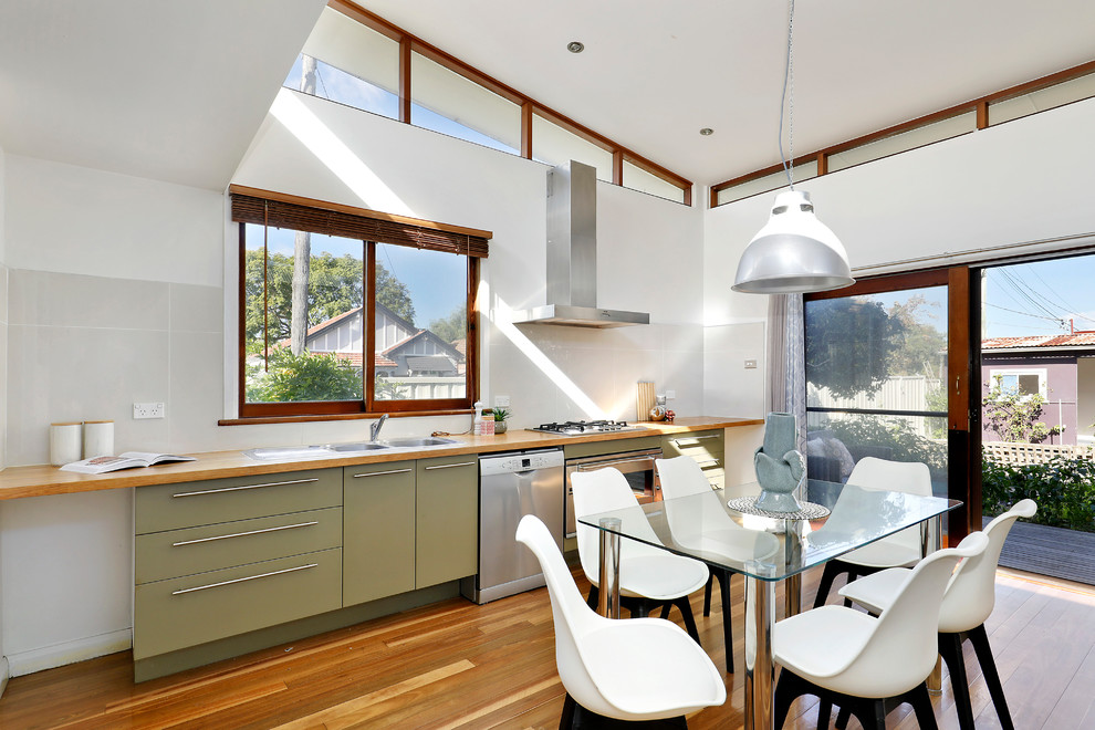 Inspiration for a midcentury single-wall eat-in kitchen in Sydney with a single-bowl sink, flat-panel cabinets, green cabinets, wood benchtops, grey splashback, ceramic splashback, stainless steel appliances, medium hardwood floors, brown floor, brown benchtop and no island.