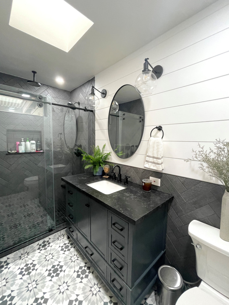 Пример оригинального дизайна: главная ванная комната среднего размера в стиле модернизм с фасадами в стиле шейкер, синими фасадами, душем в нише, раздельным унитазом, черной плиткой, керамогранитной плиткой, белыми стенами, полом из керамогранита, врезной раковиной, столешницей из кварцита, разноцветным полом, душем с раздвижными дверями, черной столешницей, тумбой под одну раковину, напольной тумбой и стенами из вагонки