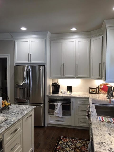 Eat-in kitchen - mid-sized transitional l-shaped dark wood floor and brown floor eat-in kitchen idea in Birmingham with an undermount sink, recessed-panel cabinets, white cabinets, white backsplash, stainless steel appliances and an island