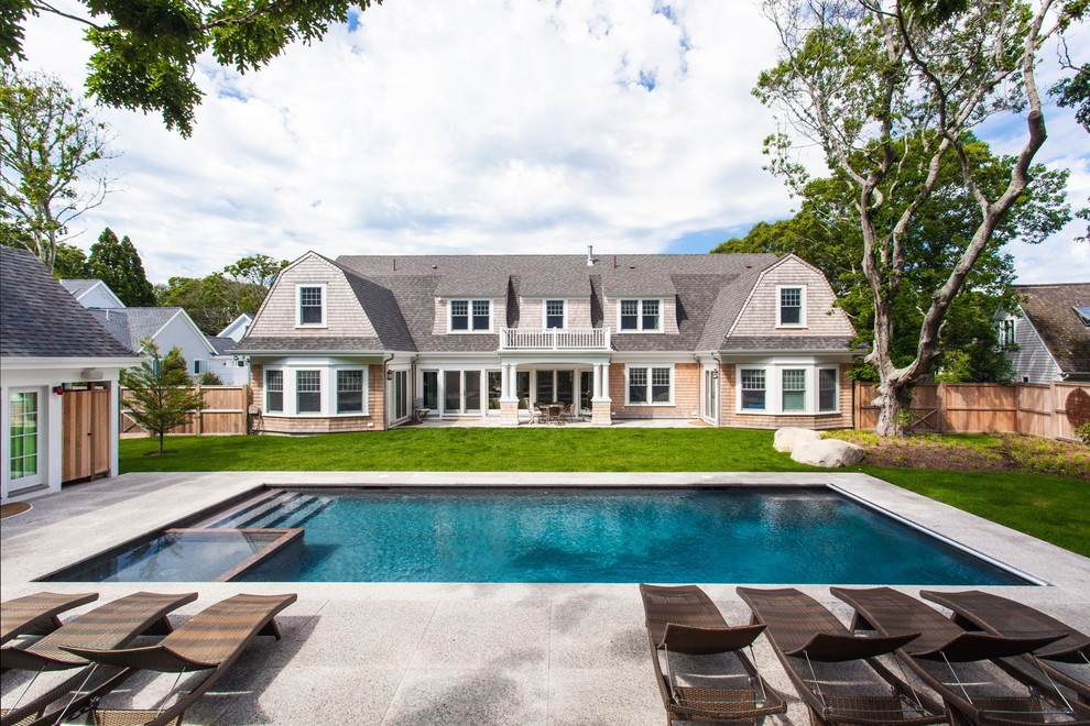 This is an example of a large traditional backyard rectangular pool in Boston with a pool house and concrete pavers.
