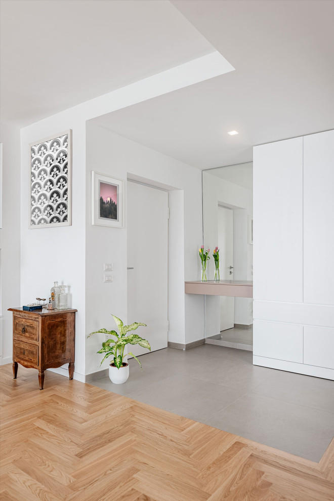 Idee per un ingresso design con pareti bianche, pavimento in gres porcellanato, una porta singola, una porta bianca, soffitto ribassato e armadio