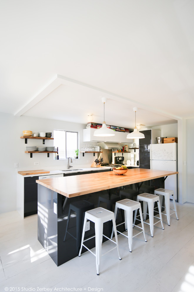 Photo of a mid-sized modern l-shaped open plan kitchen in Seattle with a single-bowl sink, flat-panel cabinets, white cabinets, wood benchtops, white splashback, stainless steel appliances, plywood floors and with island.