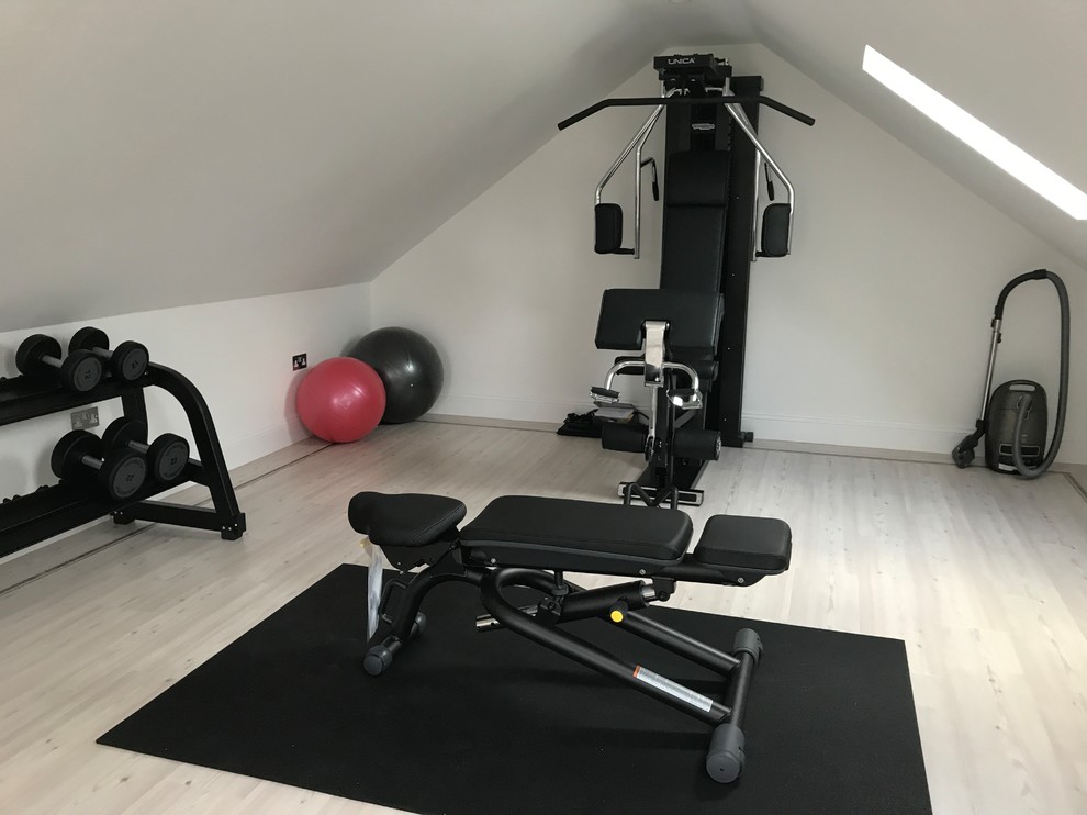 Inspiration for a small contemporary home weight room in London with beige walls, light hardwood floors and white floor.