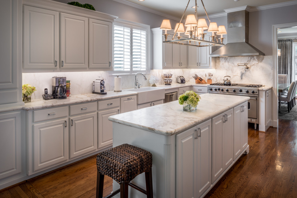 Design ideas for a large traditional l-shaped eat-in kitchen in Houston with a farmhouse sink, white cabinets, marble benchtops, white splashback, stone slab splashback, stainless steel appliances, with island and medium hardwood floors.