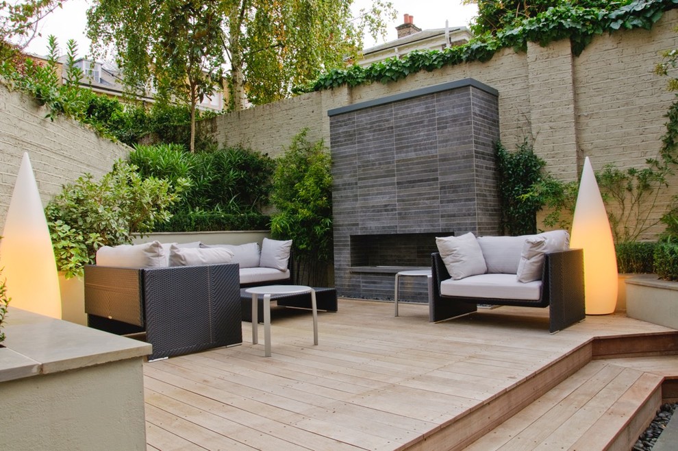 Inspiration for a small contemporary backyard patio in Hertfordshire with decking, no cover and with fireplace.