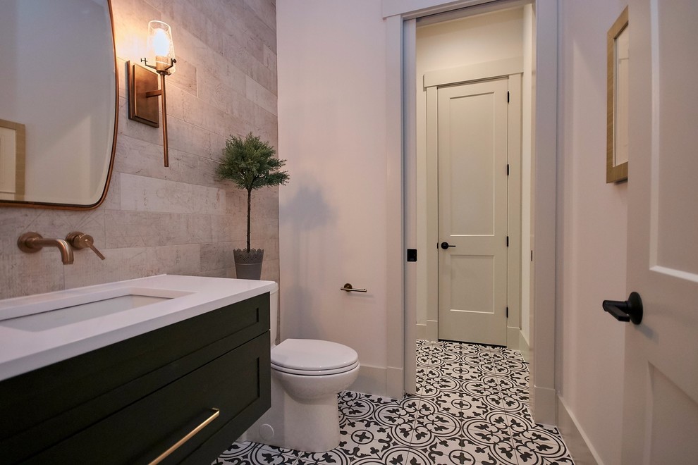 Photo of a mid-sized country powder room in DC Metro with shaker cabinets, dark wood cabinets, a two-piece toilet, beige tile, ceramic tile, white walls, cement tiles, a wall-mount sink, engineered quartz benchtops, multi-coloured floor and white benchtops.