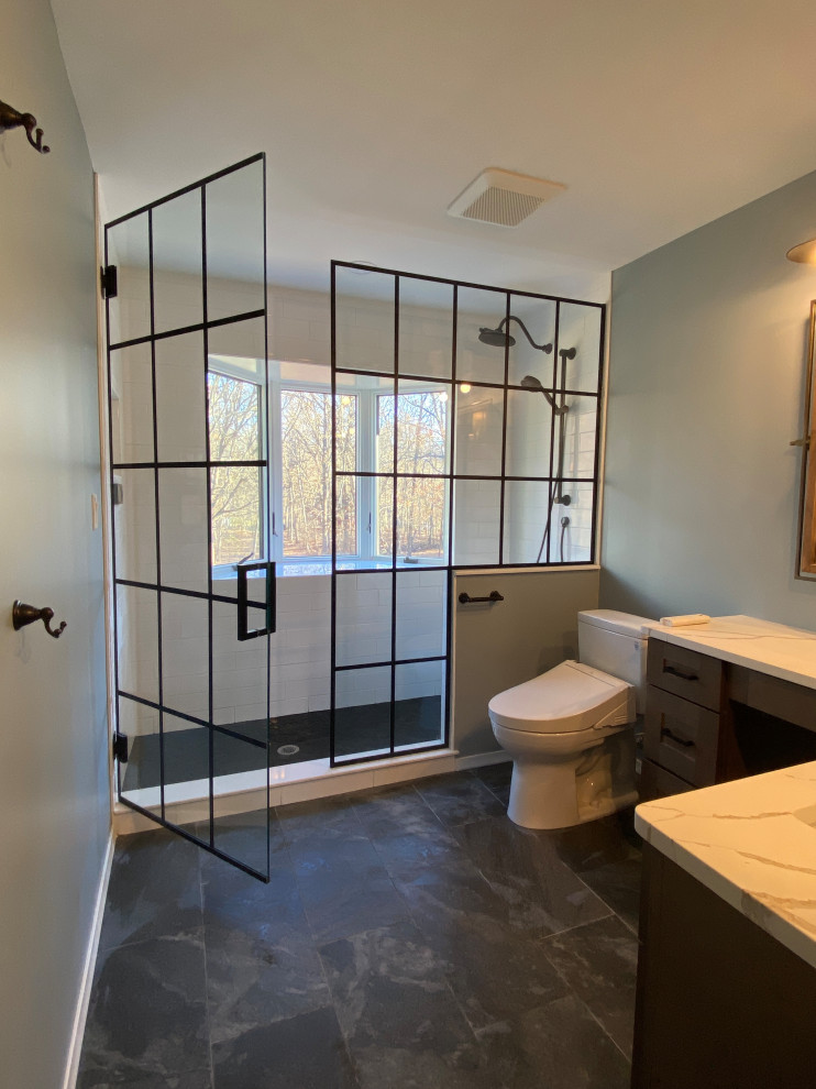 Photo of a small country master bathroom in Detroit with shaker cabinets, medium wood cabinets, an alcove shower, a bidet, blue tile, ceramic tile, blue walls, ceramic floors, engineered quartz benchtops, black floor, a hinged shower door, white benchtops, a niche, a single vanity and a built-in vanity.