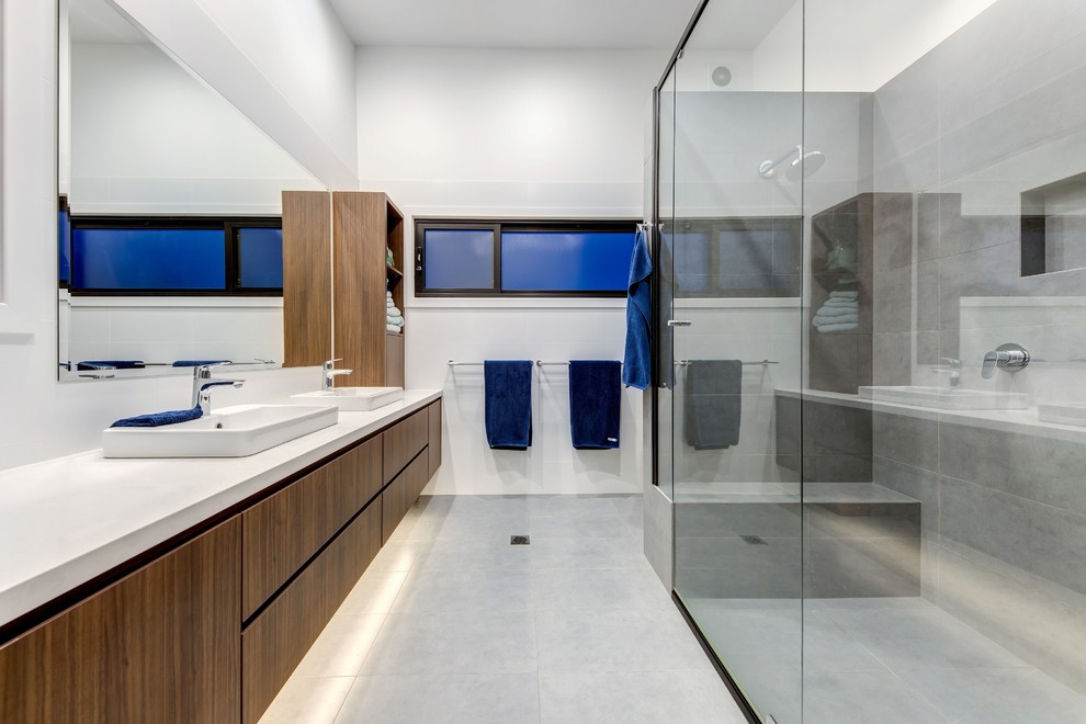 Photo of a large modern master bathroom in Sydney with brown cabinets, a double shower, white tile, ceramic floors, grey floor, a hinged shower door and white benchtops.