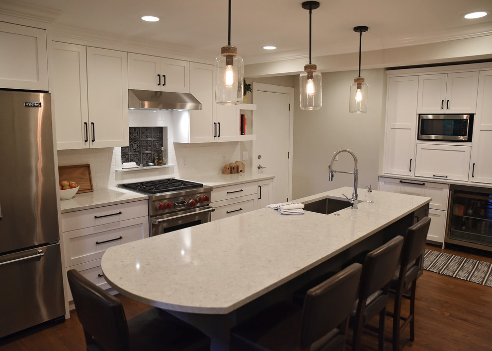 Inspiration for a mid-sized transitional enclosed kitchen remodel with an island, an undermount sink, flat-panel cabinets, white cabinets, quartz countertops, white backsplash, ceramic backsplash, stainless steel appliances and gray countertops