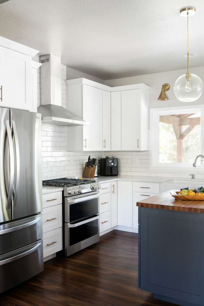 Eat-in kitchen - large transitional u-shaped dark wood floor eat-in kitchen idea in Denver with a farmhouse sink, shaker cabinets, white cabinets, quartz countertops, white backsplash, porcelain backsplash, stainless steel appliances, an island and white countertops