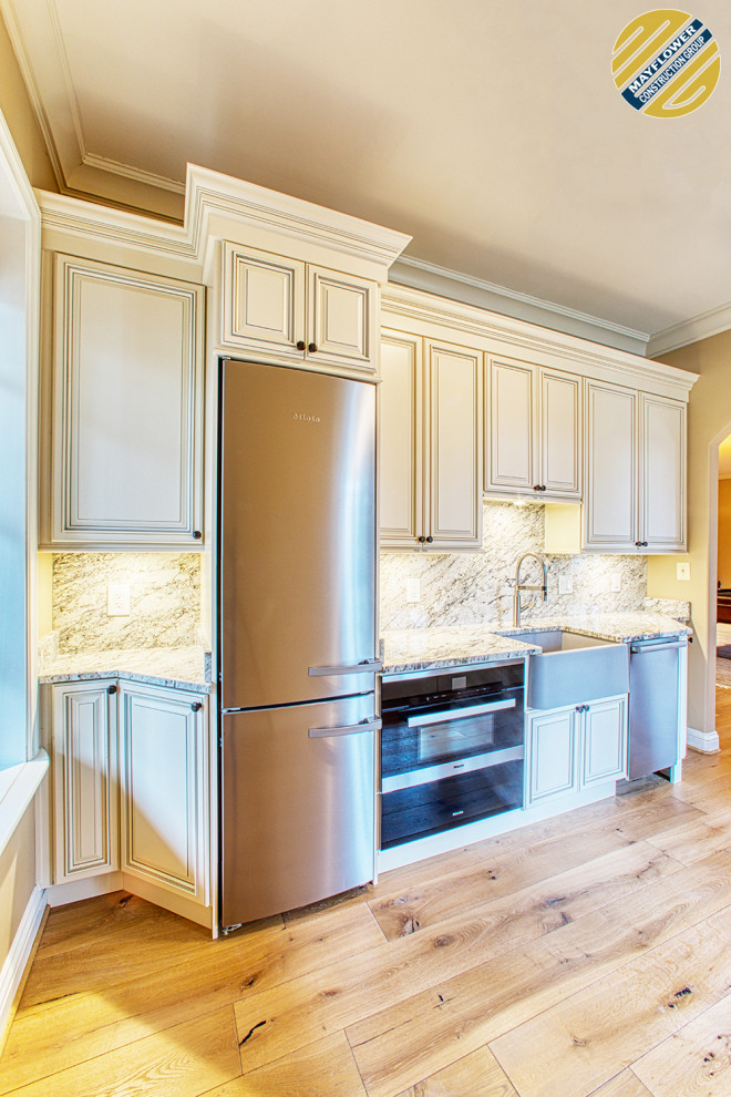Small transitional single-wall light wood floor and beige floor eat-in kitchen photo in DC Metro with a farmhouse sink, raised-panel cabinets, beige cabinets, granite countertops, gray backsplash, granite backsplash, stainless steel appliances, no island and gray countertops