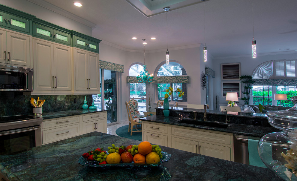 Photo of a large tropical l-shaped eat-in kitchen in Tampa with a double-bowl sink, white cabinets, granite benchtops, green splashback, stone slab splashback, stainless steel appliances and porcelain floors.