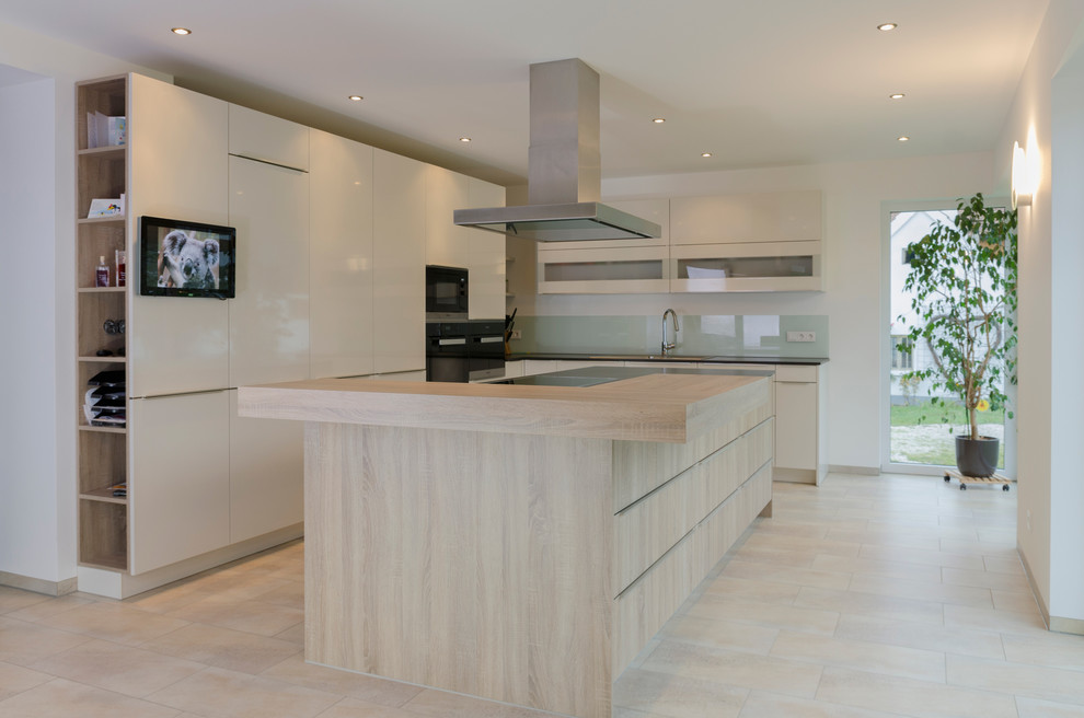 Design ideas for an expansive contemporary l-shaped eat-in kitchen in Nuremberg with flat-panel cabinets, white cabinets, wood benchtops, white splashback, glass sheet splashback, stainless steel appliances, with island and limestone floors.