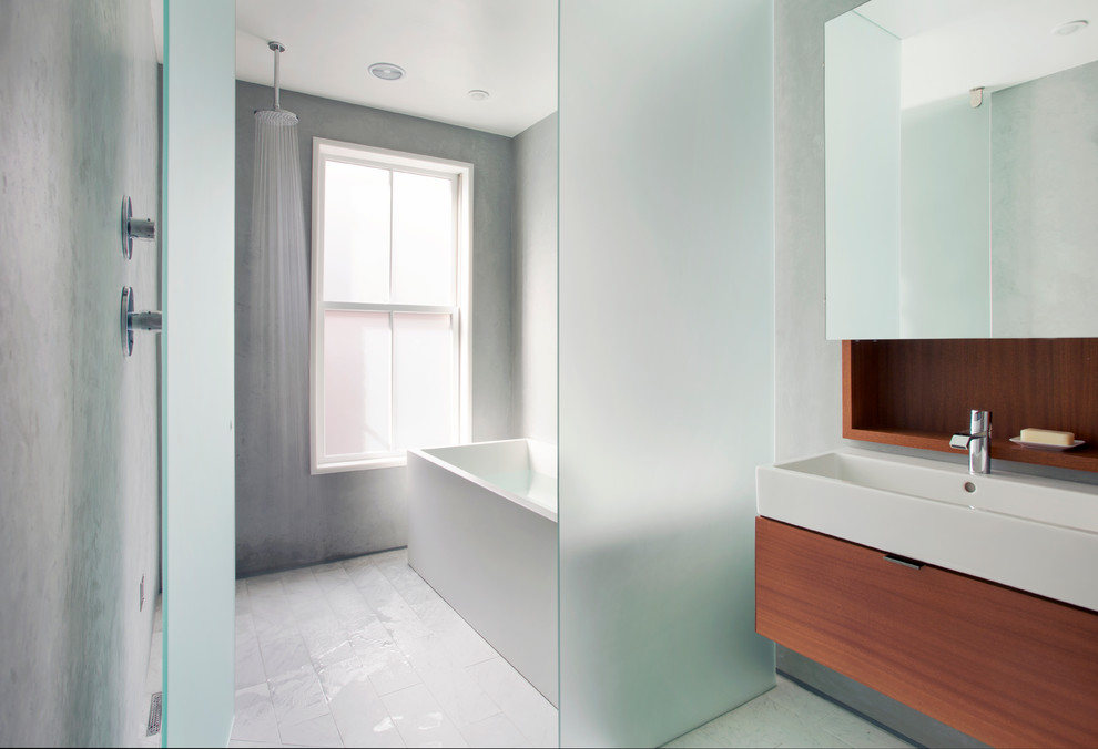 Photo of a contemporary master bathroom in Boston with a trough sink, flat-panel cabinets, medium wood cabinets, a freestanding tub, an open shower, gray tile, grey walls and a hinged shower door.