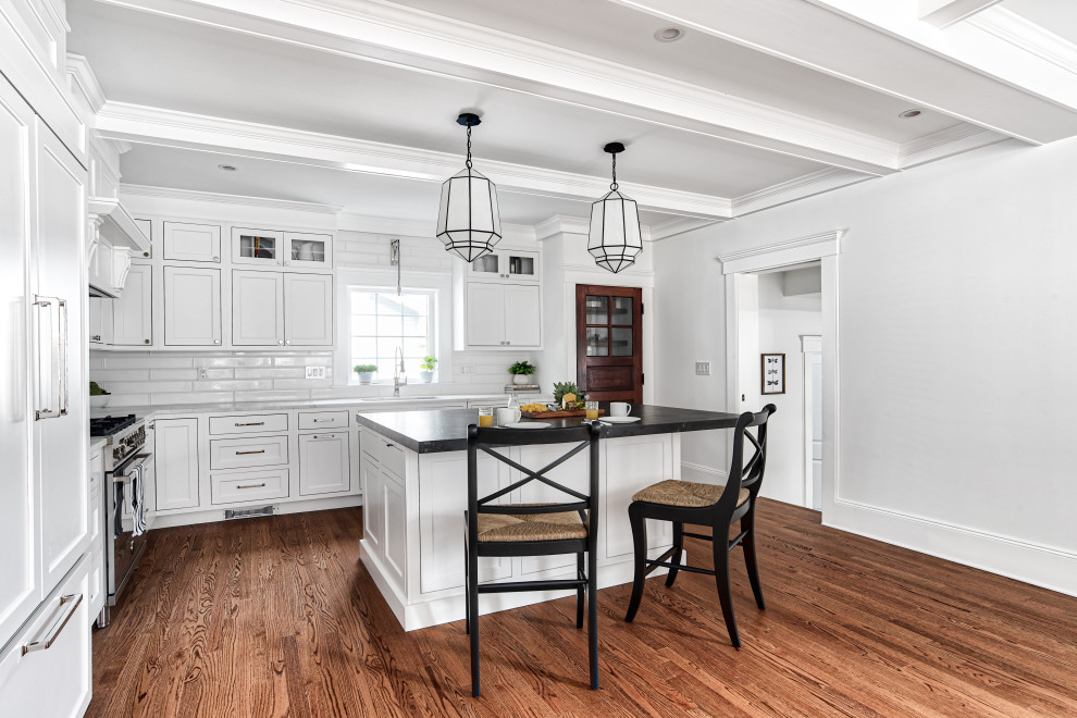 Design ideas for a large traditional l-shaped eat-in kitchen in New York with an undermount sink, shaker cabinets, white cabinets, marble benchtops, white splashback, subway tile splashback, panelled appliances, medium hardwood floors, with island, brown floor and white benchtop.