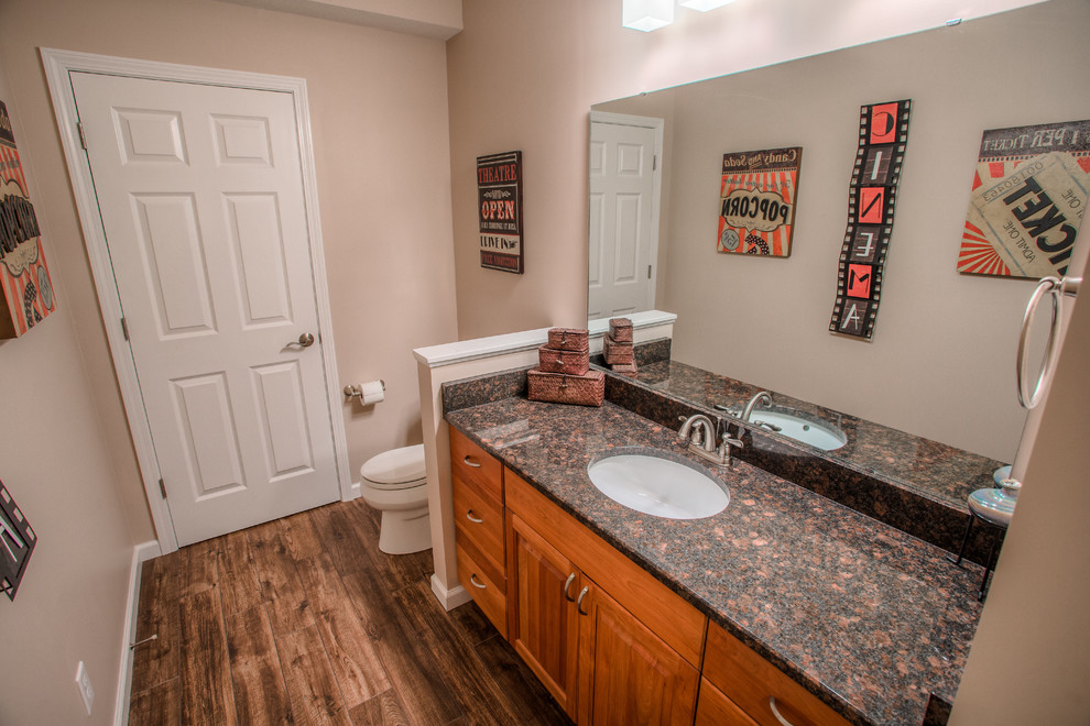 This is an example of a transitional kids bathroom in Other with shaker cabinets, medium wood cabinets, beige walls, medium hardwood floors, a drop-in sink and granite benchtops.