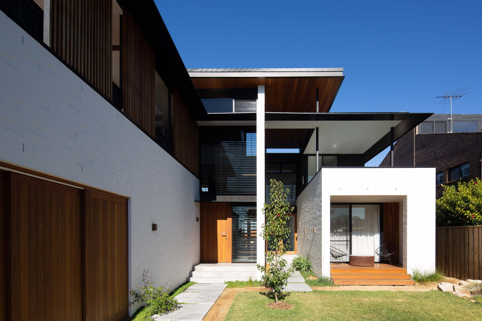 Photo of a contemporary three-storey brick white house exterior in Sydney with a flat roof.