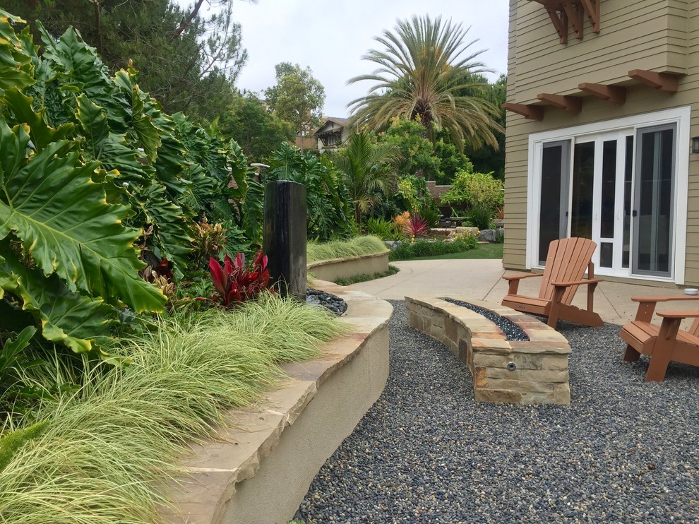 Photo of a mid-sized tropical backyard full sun formal garden in San Diego with a fire feature and gravel.