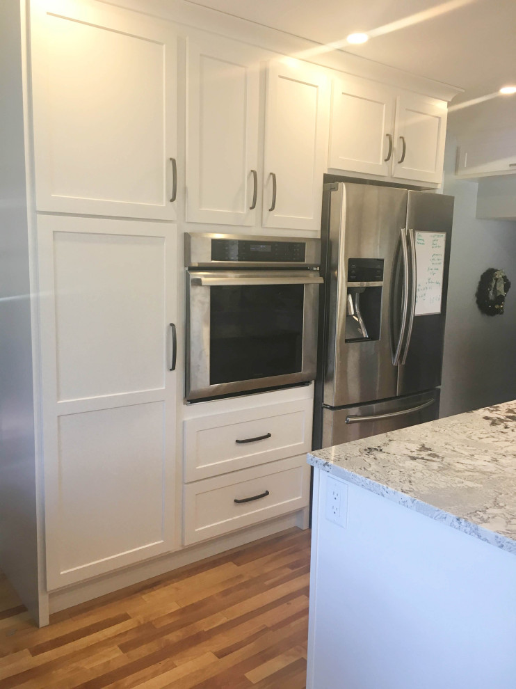 Mid-sized transitional u-shaped medium tone wood floor and brown floor eat-in kitchen photo with recessed-panel cabinets, white cabinets, granite countertops, stainless steel appliances, an island and multicolored countertops