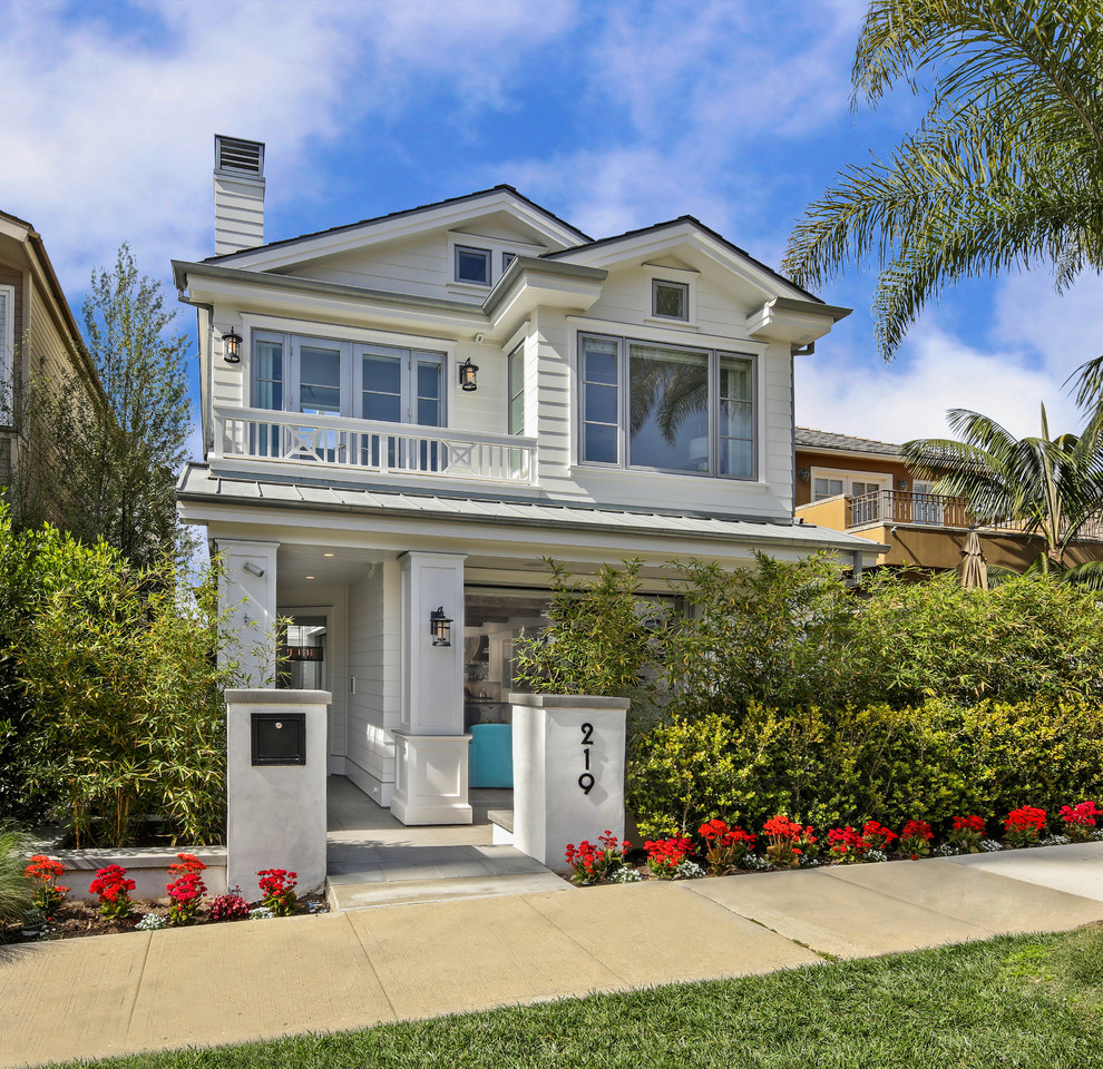 This is an example of a beach style two-storey white house exterior in Orange County with a gable roof.