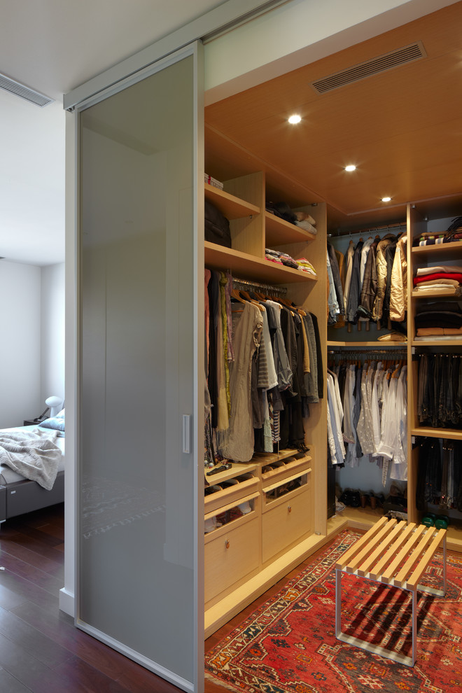 Mid-sized transitional gender-neutral walk-in wardrobe in Barcelona with open cabinets, carpet and light wood cabinets.