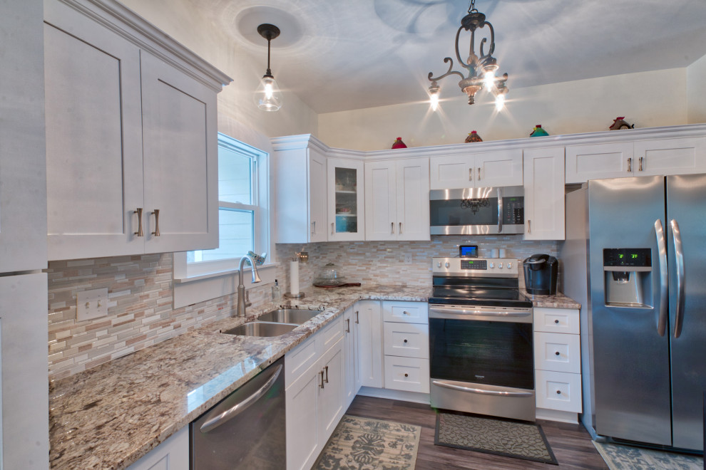 Inspiration for a mid-sized l-shaped eat-in kitchen remodel with an undermount sink, shaker cabinets, yellow cabinets, granite countertops, glass tile backsplash, stainless steel appliances, an island and white countertops