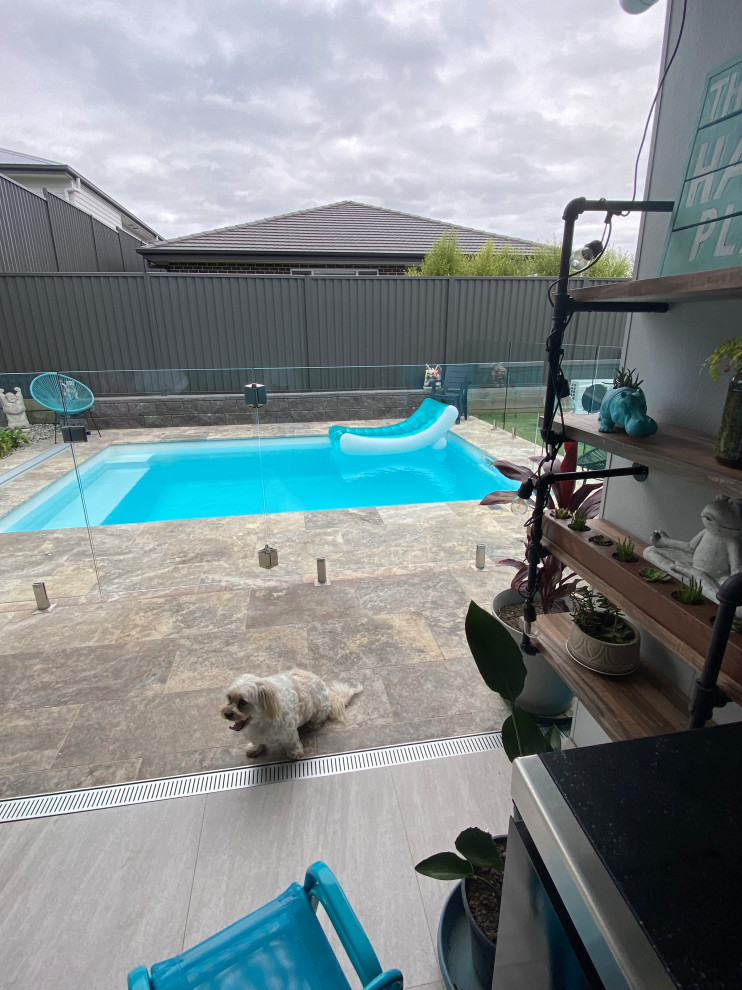 Design ideas for a mid-sized beach style backyard rectangular pool in Wollongong with natural stone pavers.
