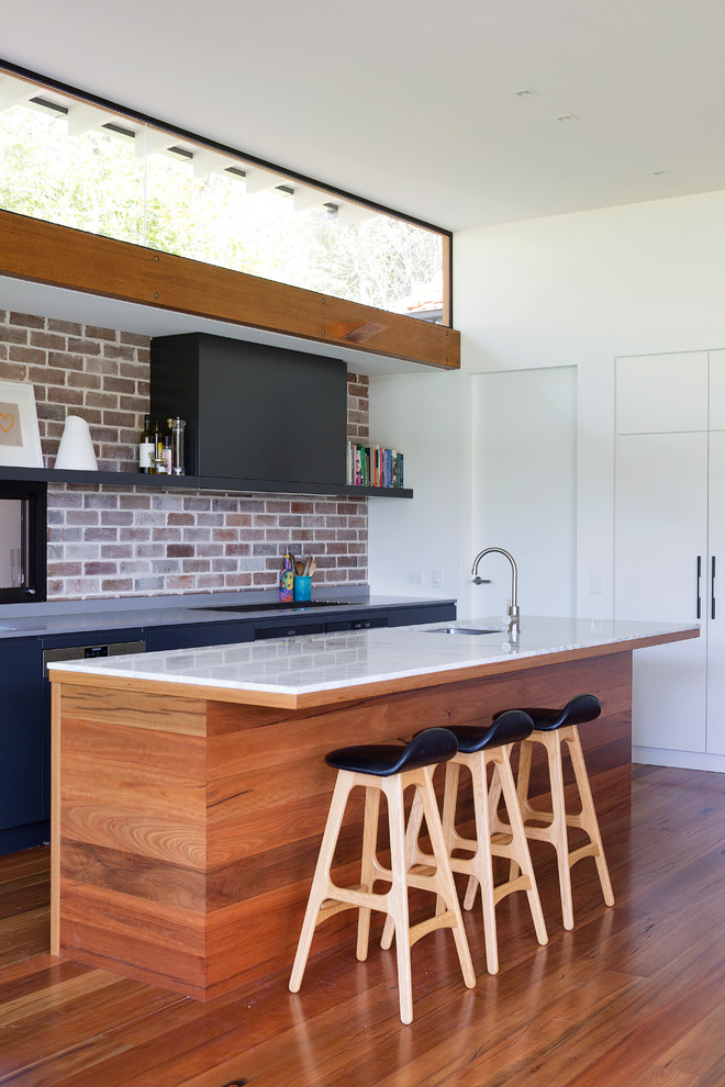 This is an example of a large contemporary galley open plan kitchen in Sydney with an undermount sink, marble benchtops, stainless steel appliances, medium hardwood floors and with island.