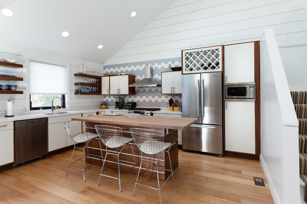 Small transitional light wood floor eat-in kitchen photo with a double-bowl sink, blue backsplash, stainless steel appliances and an island