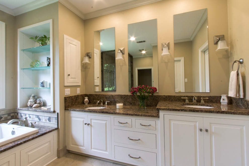 Inspiration for a mid-sized traditional master bathroom in New Orleans with an undermount sink, raised-panel cabinets, white cabinets, granite benchtops, a drop-in tub, a corner shower, a two-piece toilet, beige tile, porcelain tile, beige walls and porcelain floors.