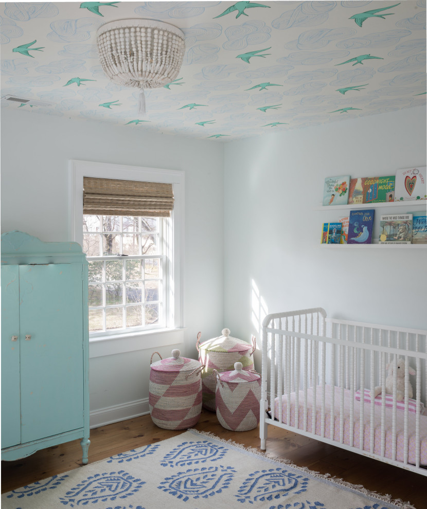 Cette image montre une grande chambre de bébé fille marine avec un mur blanc, parquet clair, un sol marron et un plafond en papier peint.