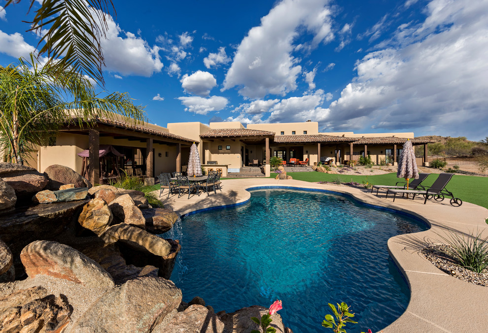 Inspiration for a transitional backyard kidney-shaped natural pool in Phoenix with a water slide and decking.