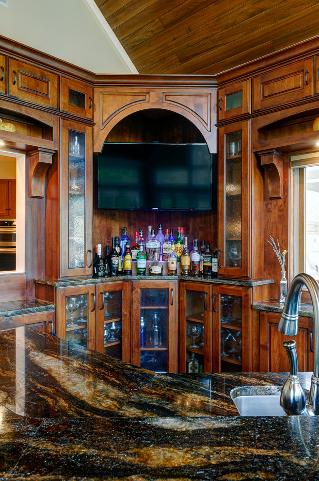 Inspiration for a traditional u-shaped seated home bar in Columbus with an undermount sink, raised-panel cabinets, dark wood cabinets, granite benchtops and cork floors.