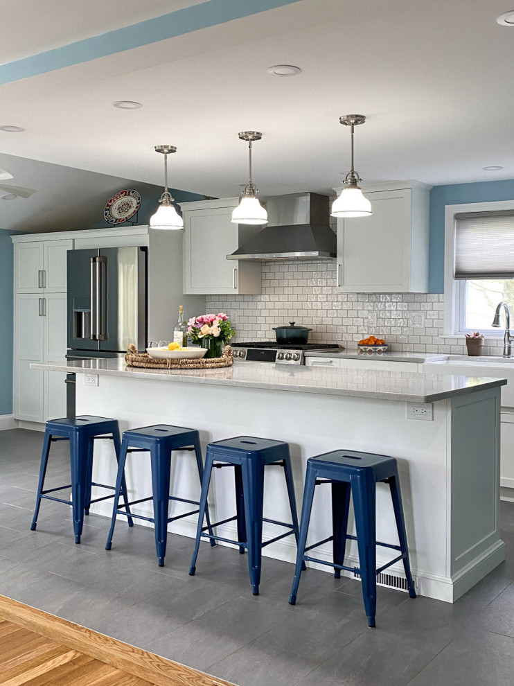 Transitional eat-in kitchen in Boston with a farmhouse sink, raised-panel cabinets, white cabinets, quartz benchtops, white splashback, ceramic splashback, stainless steel appliances, porcelain floors, with island, grey floor and white benchtop.