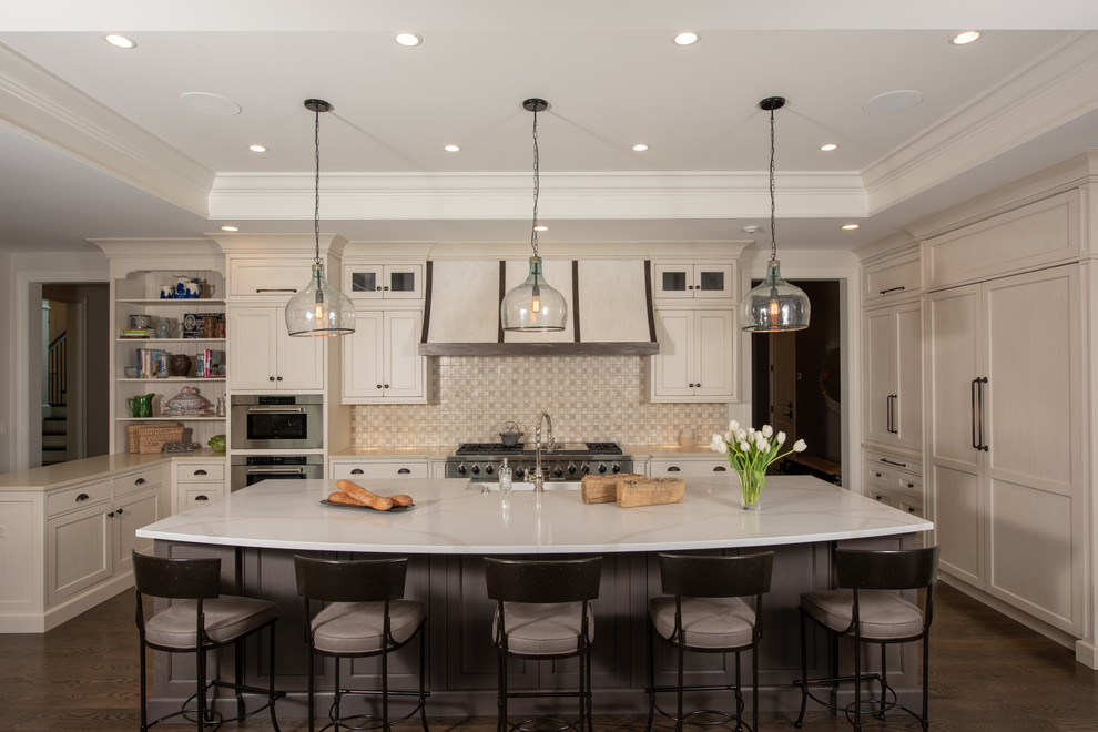 This is an example of a mid-sized traditional kitchen in Chicago with a farmhouse sink, beige cabinets, quartzite benchtops, beige splashback, porcelain splashback, panelled appliances, dark hardwood floors, with island, white benchtop and shaker cabinets.