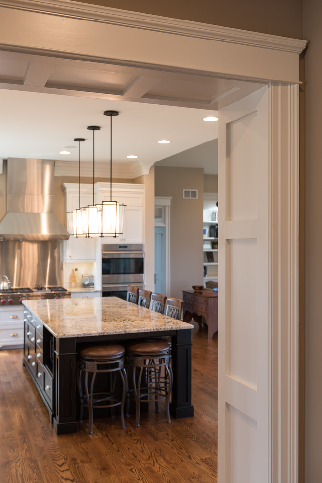 Example of a mid-sized transitional l-shaped dark wood floor and brown floor open concept kitchen design with an undermount sink, shaker cabinets, white cabinets, granite countertops, stainless steel appliances and an island