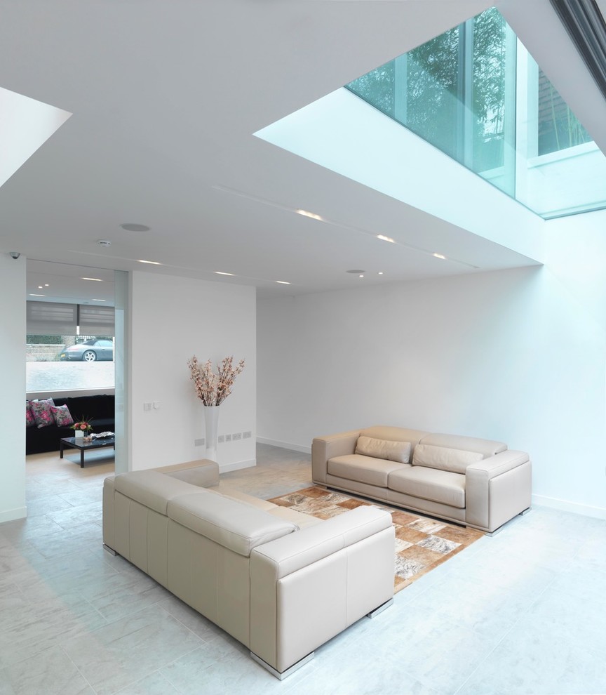 Large contemporary formal open concept living room in London with white walls, limestone floors, a wall-mounted tv and grey floor.
