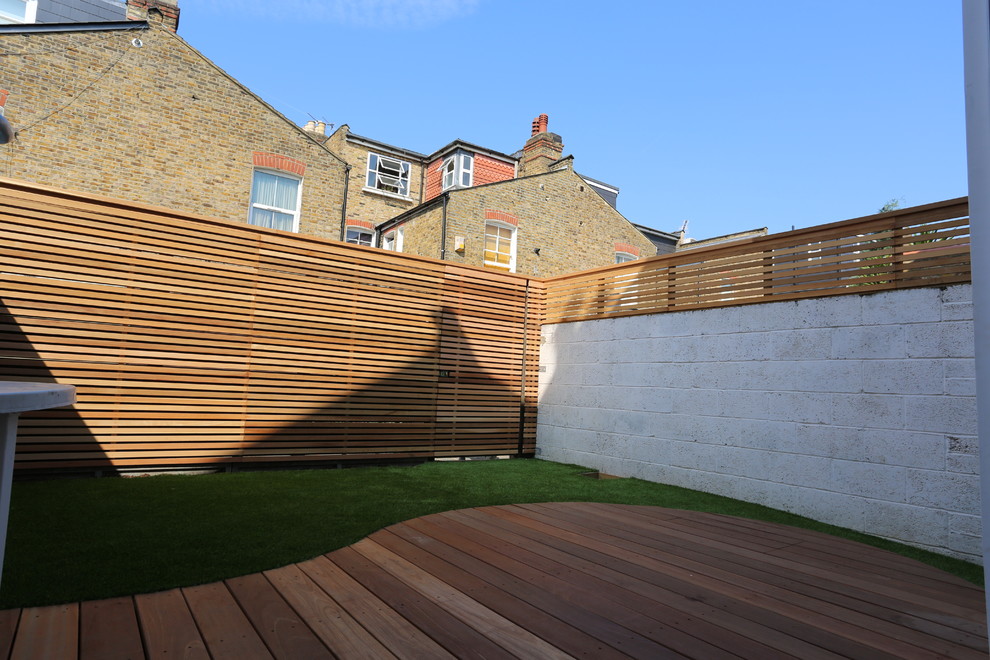 This is an example of a small modern backyard shaded formal garden in London with decking.