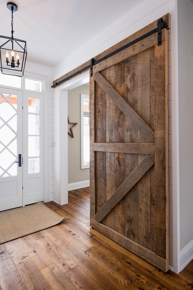Inspiration for a large transitional foyer in Toronto with white walls, medium hardwood floors, a single front door, a white front door and brown floor.