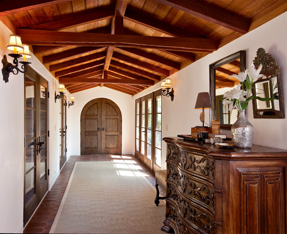 Inspiration for a large mediterranean hallway in Santa Barbara with white walls and terra-cotta floors.