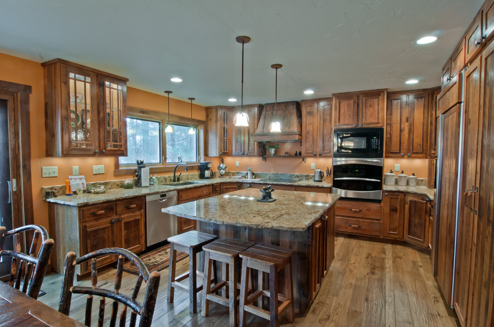 Eat-in kitchen - rustic u-shaped eat-in kitchen idea with an undermount sink, raised-panel cabinets, medium tone wood cabinets, granite countertops, beige backsplash and stainless steel appliances