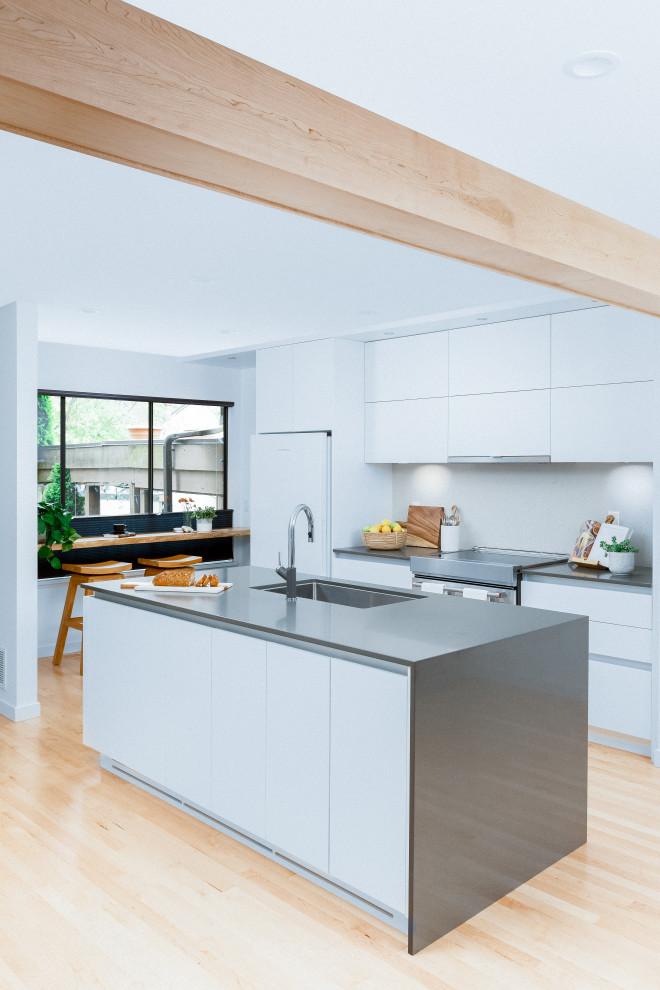 Photo of a small modern single-wall kitchen in Vancouver with an undermount sink, recessed-panel cabinets, white cabinets, quartz benchtops, grey splashback, light hardwood floors, with island, beige floor, grey benchtop and exposed beam.