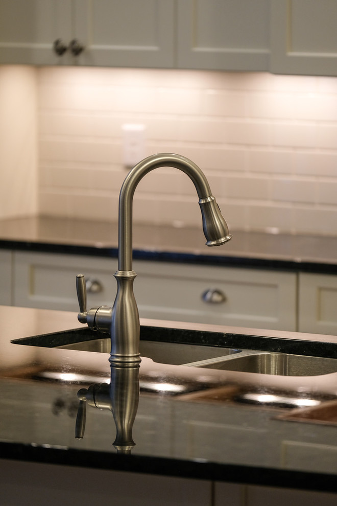 Large transitional l-shaped dark wood floor and brown floor eat-in kitchen photo with an undermount sink, recessed-panel cabinets, white cabinets, granite countertops, white backsplash, stainless steel appliances, an island and blue countertops