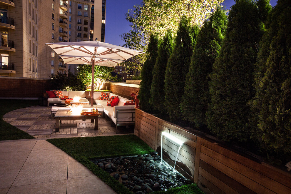 Large contemporary rooftop deck in Chicago with a water feature and an awning.