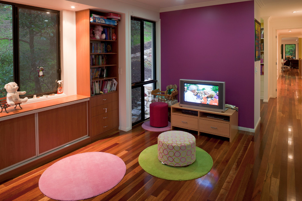 This is an example of a small contemporary kids' playroom for kids 4-10 years old and girls in Brisbane with purple walls and medium hardwood floors.