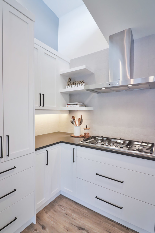 Example of a large transitional l-shaped vinyl floor and brown floor open concept kitchen design in Vancouver with an undermount sink, flat-panel cabinets, white cabinets, quartz countertops, gray backsplash, porcelain backsplash, stainless steel appliances and an island