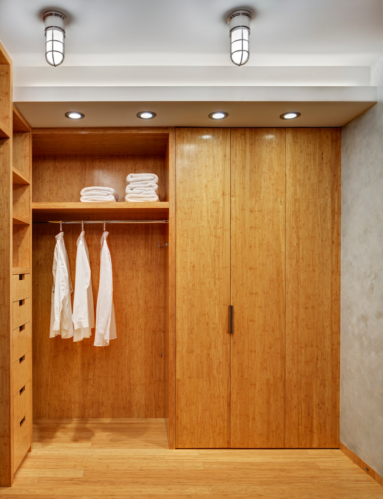 This is an example of a small contemporary gender-neutral walk-in wardrobe in New York with open cabinets, light wood cabinets and bamboo floors.